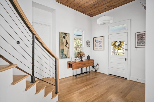 entryway featuring wooden ceiling, baseboards, stairs, and light wood-style floors