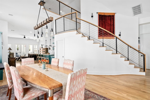 dining room featuring visible vents, stairway, a high ceiling, and wood finished floors