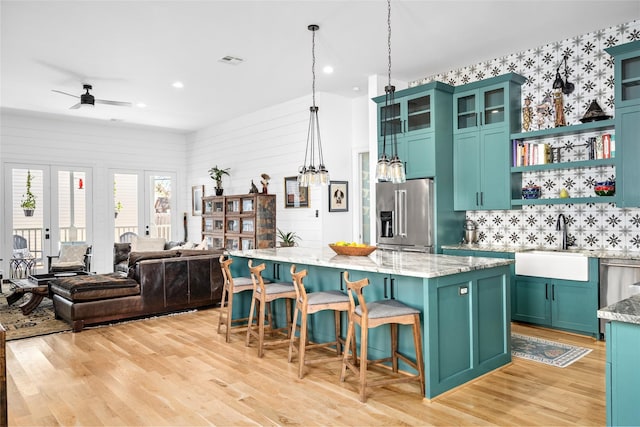 kitchen featuring visible vents, a kitchen island, light wood-type flooring, high quality fridge, and a sink