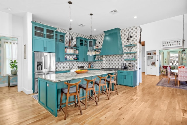 kitchen with visible vents, premium range hood, appliances with stainless steel finishes, light wood-style floors, and open shelves