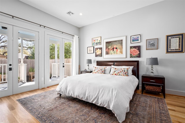 bedroom featuring visible vents, wood finished floors, french doors, and access to outside