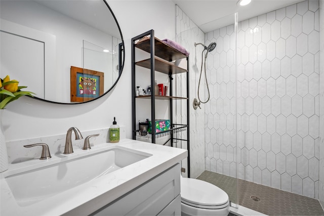 bathroom with a tile shower, toilet, and vanity