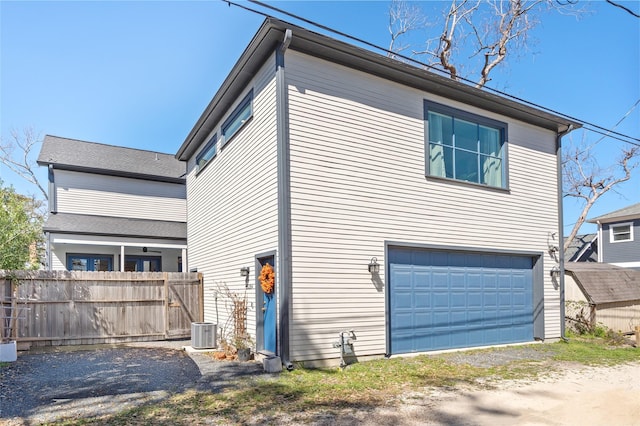 view of side of property with an attached garage, fence, and central AC