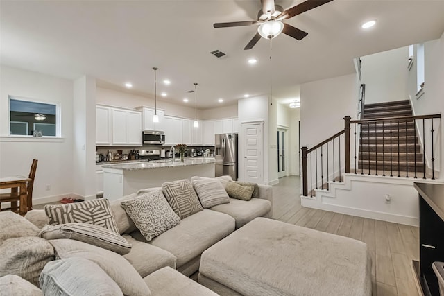 living room featuring light hardwood / wood-style flooring and ceiling fan