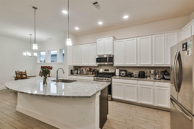 kitchen featuring sink, white cabinetry, stainless steel appliances, and decorative light fixtures