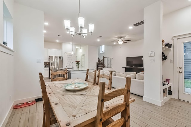 dining area featuring ceiling fan with notable chandelier and sink