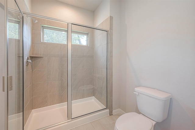 bathroom featuring tile patterned floors, plenty of natural light, a shower with shower door, and toilet