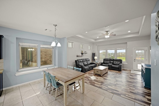 dining area with light tile patterned floors, a raised ceiling, visible vents, and baseboards