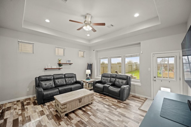 living room featuring a healthy amount of sunlight, light wood-type flooring, and a tray ceiling