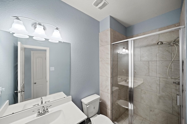 full bath featuring visible vents, a textured wall, toilet, a shower stall, and vanity