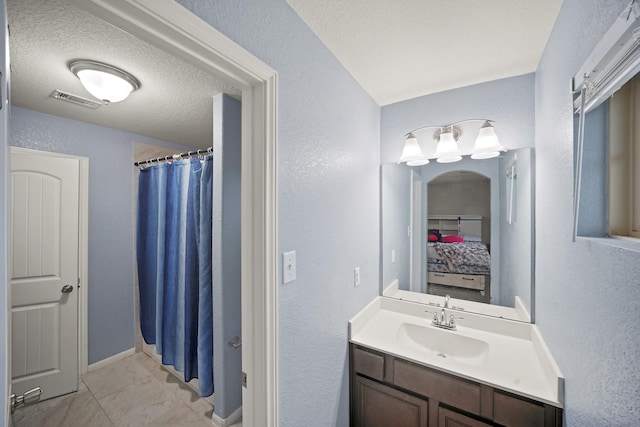 ensuite bathroom with visible vents, a shower with shower curtain, ensuite bathroom, vanity, and a textured ceiling