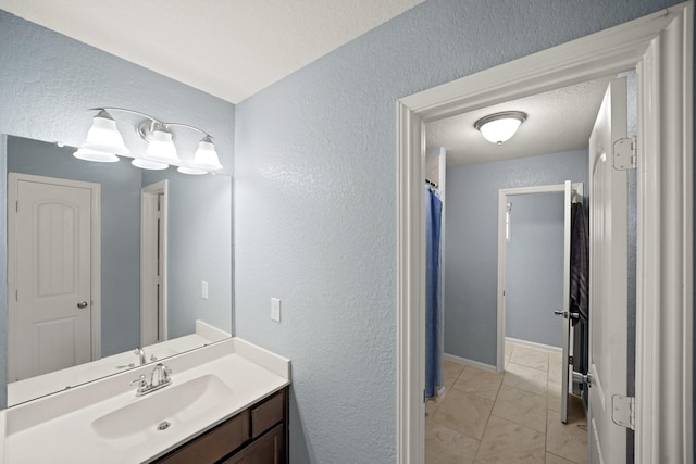 bathroom with a textured wall, vanity, and a textured ceiling