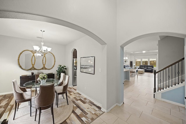 dining area with baseboards, visible vents, a chandelier, and arched walkways