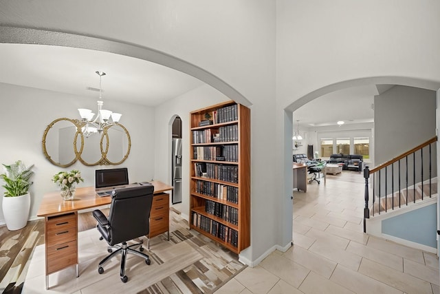 office featuring a chandelier, arched walkways, visible vents, and baseboards