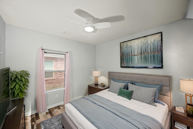 bedroom featuring visible vents, ceiling fan, baseboards, and wood finished floors