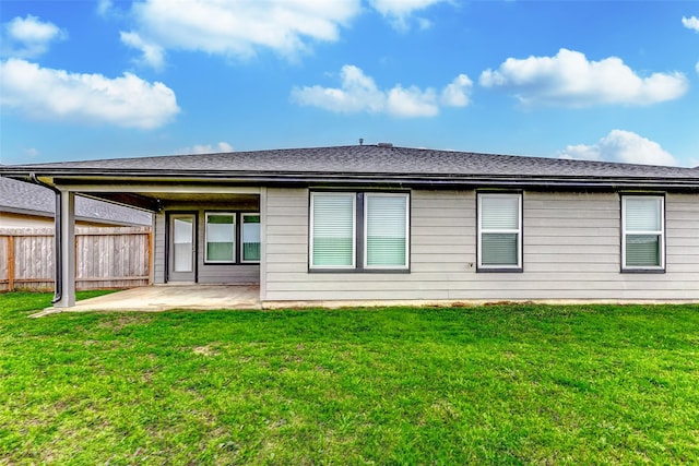 rear view of house featuring a yard, a shingled roof, a patio area, and fence