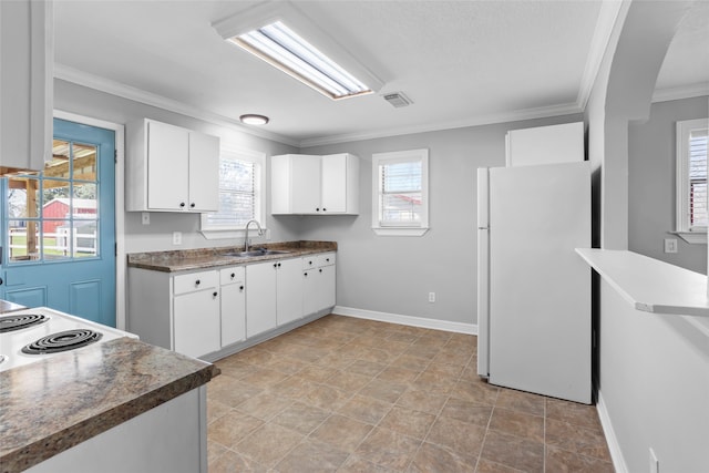 kitchen featuring a sink, white cabinetry, freestanding refrigerator, crown molding, and baseboards