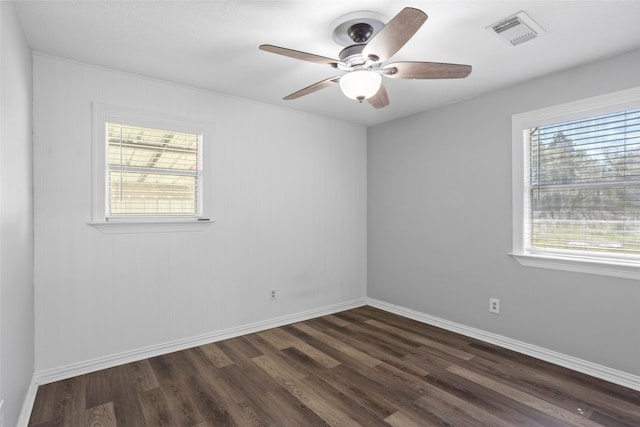 spare room featuring dark wood-style floors, visible vents, ceiling fan, and baseboards