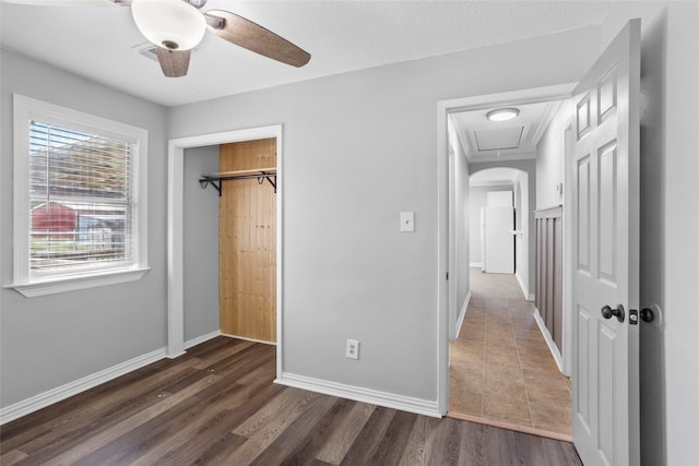 unfurnished bedroom with baseboards, dark wood-style flooring, freestanding refrigerator, ceiling fan, and a closet