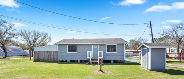 rear view of house featuring an outbuilding, a lawn, and fence