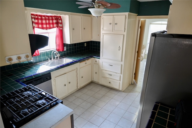 kitchen with tasteful backsplash, tile countertops, stainless steel appliances, ceiling fan, and sink