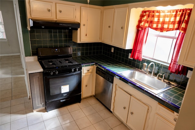 kitchen with sink, tile counters, dishwasher, and black gas range