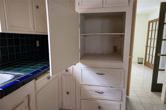 kitchen with light tile patterned flooring, tasteful backsplash, white cabinetry, and tile counters