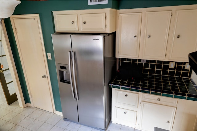 kitchen featuring tile counters, light tile patterned floors, tasteful backsplash, and stainless steel refrigerator with ice dispenser
