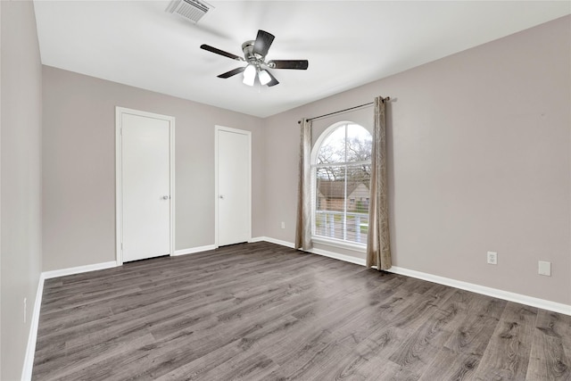 unfurnished bedroom featuring a ceiling fan, wood finished floors, visible vents, and baseboards