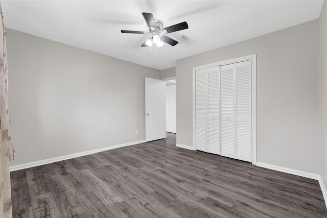 unfurnished bedroom with dark wood-style floors, a closet, visible vents, ceiling fan, and baseboards