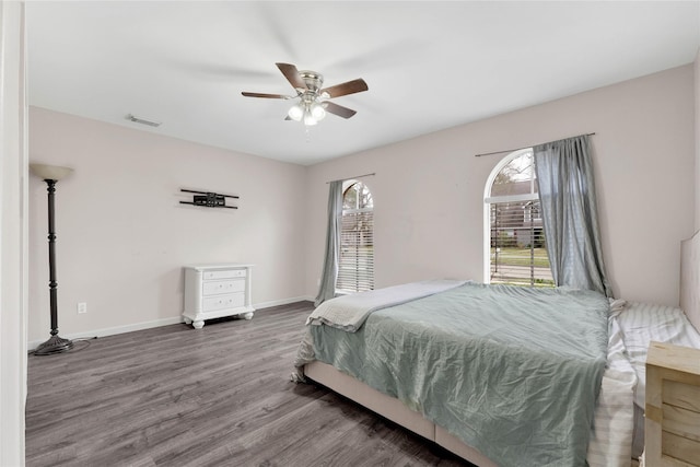 bedroom with a ceiling fan, baseboards, visible vents, and wood finished floors