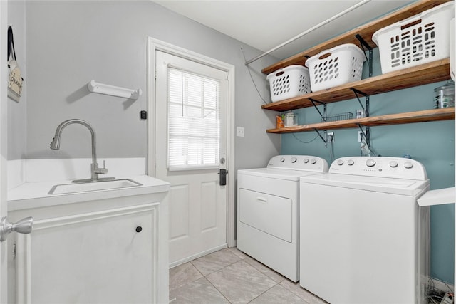 laundry area featuring washing machine and dryer, light tile patterned flooring, and a sink