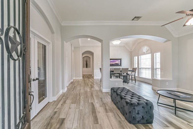 entrance foyer with ceiling fan, ornamental molding, light wood-type flooring, and lofted ceiling