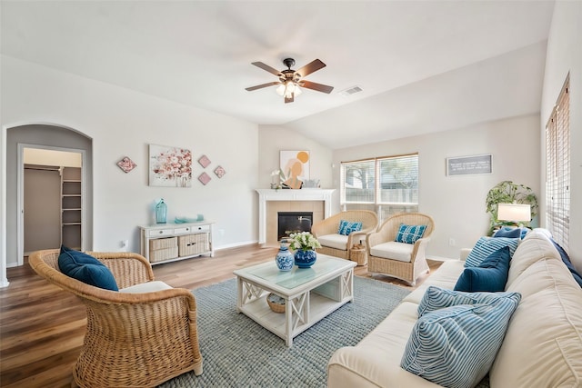 living room with a tiled fireplace, lofted ceiling, ceiling fan, and wood-type flooring