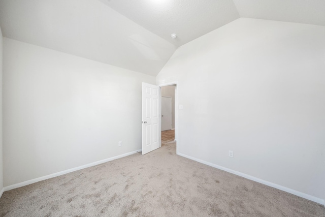 carpeted empty room with lofted ceiling