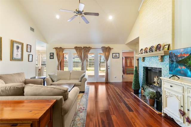 living room with a fireplace, ceiling fan, dark wood-type flooring, and high vaulted ceiling