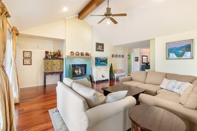 living room featuring beamed ceiling, dark hardwood / wood-style floors, a tiled fireplace, ceiling fan, and high vaulted ceiling