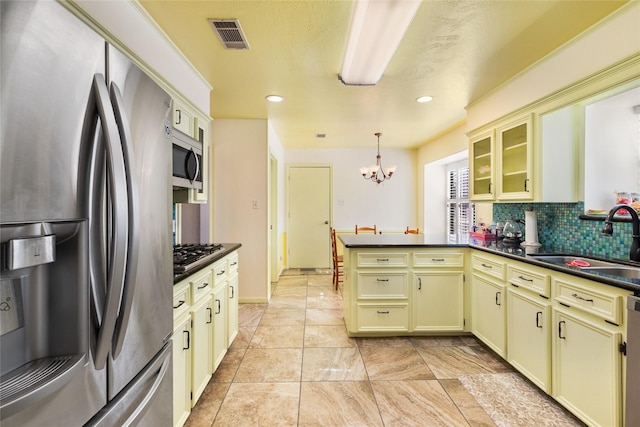 kitchen featuring cream cabinets, stainless steel appliances, sink, backsplash, and pendant lighting