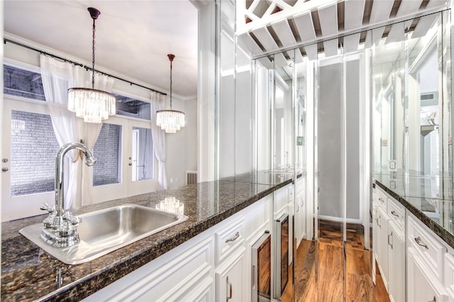 kitchen featuring white cabinets, pendant lighting, sink, and dark stone counters