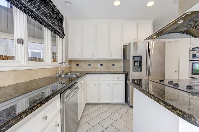 kitchen featuring exhaust hood, stainless steel appliances, dark stone counters, sink, and white cabinetry