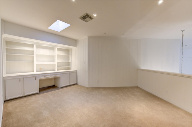 unfurnished office with a skylight and light colored carpet