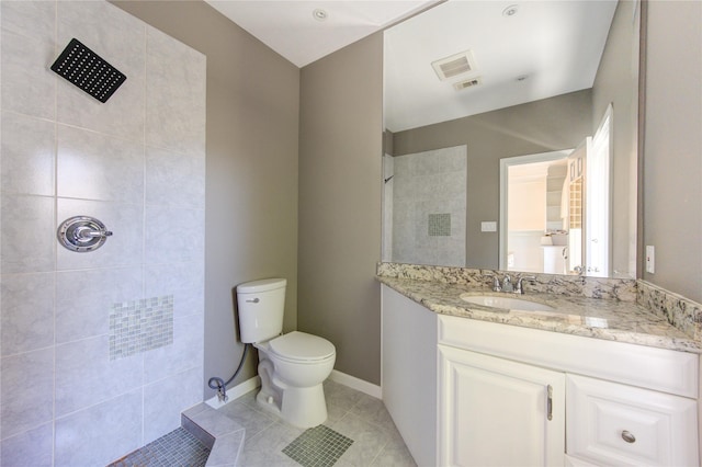 bathroom featuring toilet, a tile shower, tile patterned floors, and vanity