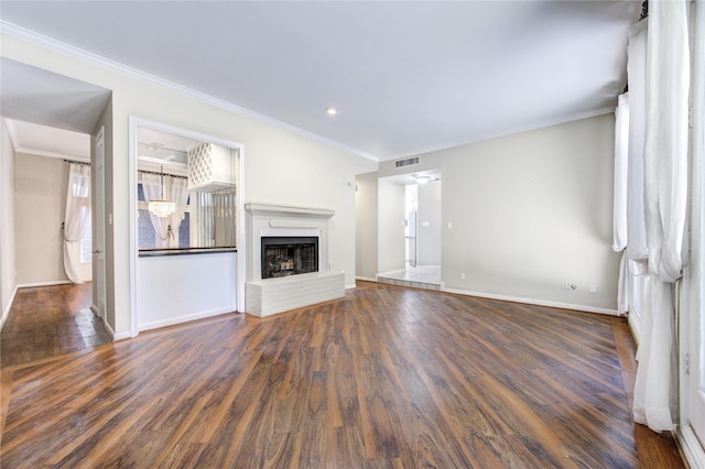 unfurnished living room featuring a brick fireplace, crown molding, and dark hardwood / wood-style floors