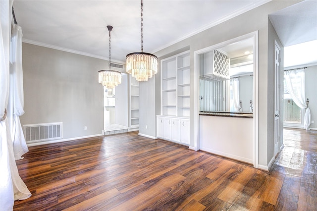 unfurnished dining area featuring an inviting chandelier, crown molding, built in shelves, and dark hardwood / wood-style floors