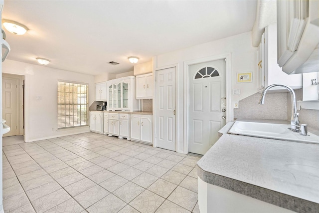 kitchen with white cabinets, light tile patterned floors, and sink