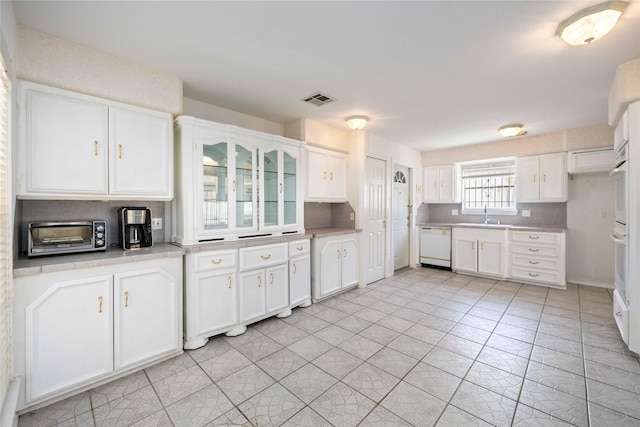 kitchen with white appliances, light tile patterned floors, sink, backsplash, and white cabinetry