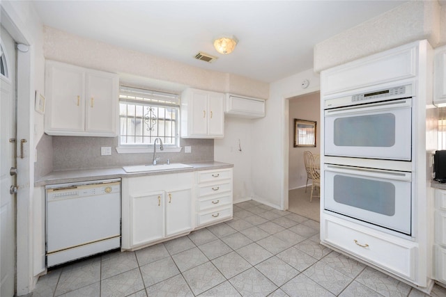 kitchen with white appliances, light tile patterned floors, sink, backsplash, and white cabinets