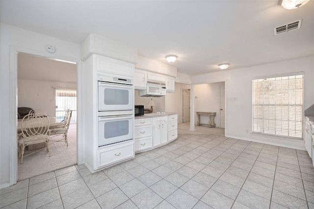 kitchen featuring white cabinets, light tile patterned floors, and white appliances