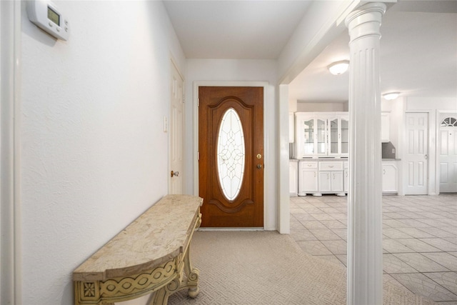 foyer with ornate columns and light carpet