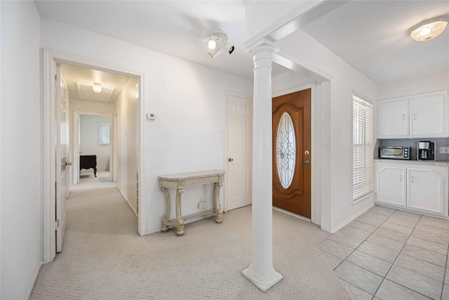 foyer featuring ornate columns and light carpet